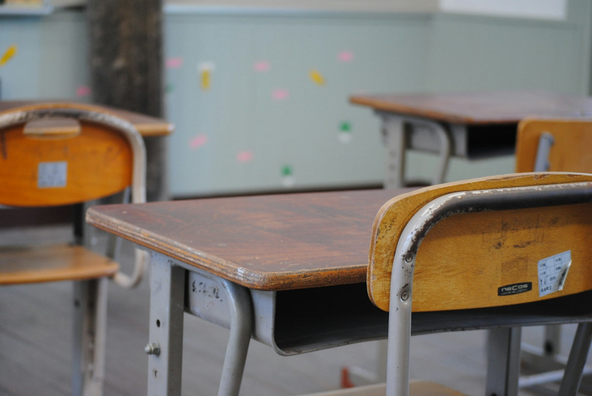 A row of wooden school desks in a classroom